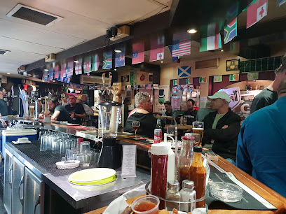 Johnny Fox's Pub bar interior with patrons, draft beers and flags