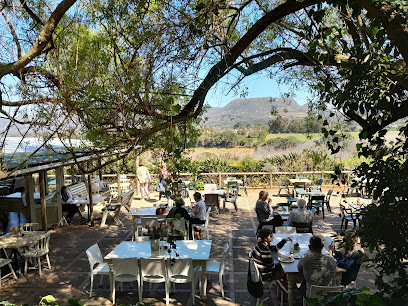 Chart Farm Coffee Shop outdoor garden seating under trees with diners and mountain view