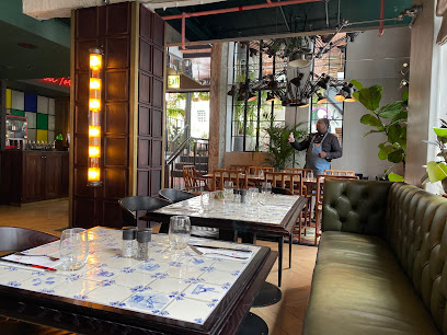 Gigi Rooftop Restaurant & Bar interior with blue-tiled tables and green banquette