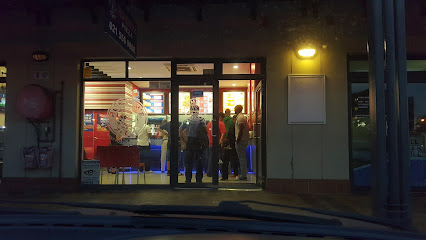 Roman's Pizza Parklands storefront at dusk with customers ordering at the counter