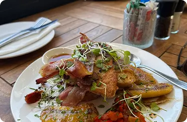 Brunch plate with bacon, roasted potatoes, microgreens and grilled tomato