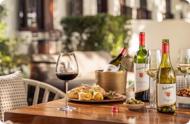 Nederburg wine bottles, glasses and appetizers on outdoor dining table