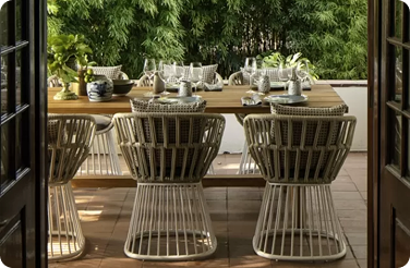 Outdoor dining table with woven rattan chairs and table settings