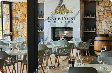 Cape Point Vineyards tasting room with set tables, wine bottles and barrel