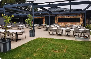 Outdoor restaurant patio with empty tables under metal pergola