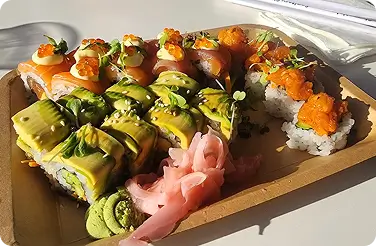 Assorted sushi tray with avocado rolls, salmon-topped rolls, tobiko, ginger, wasabi